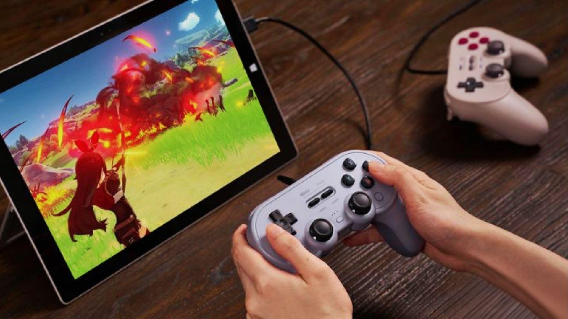 Person using wireless controller to play vibrant action game on tablet at wooden desk on PlayBattleSquare