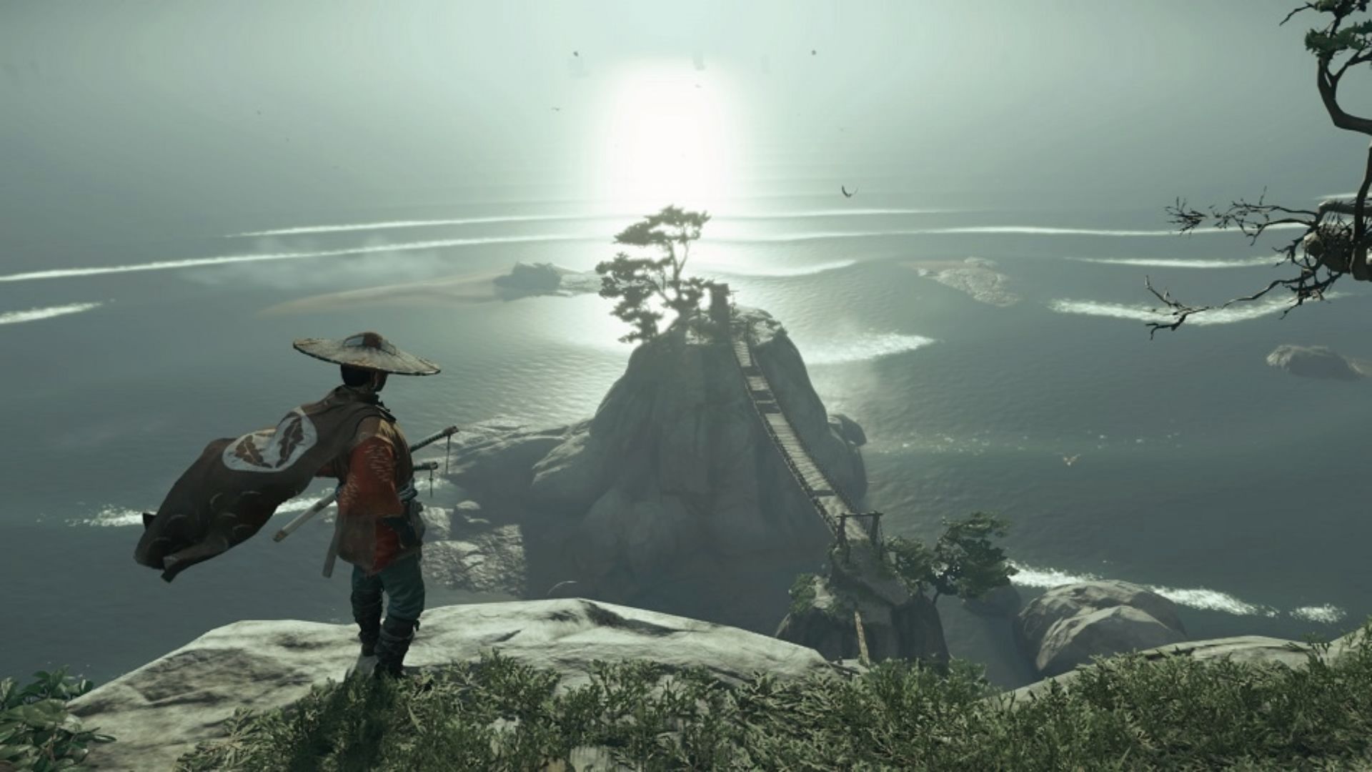 Lone samurai Jin gazes at a misty island bridge in Ghost of Tsushima’s haunting open world.