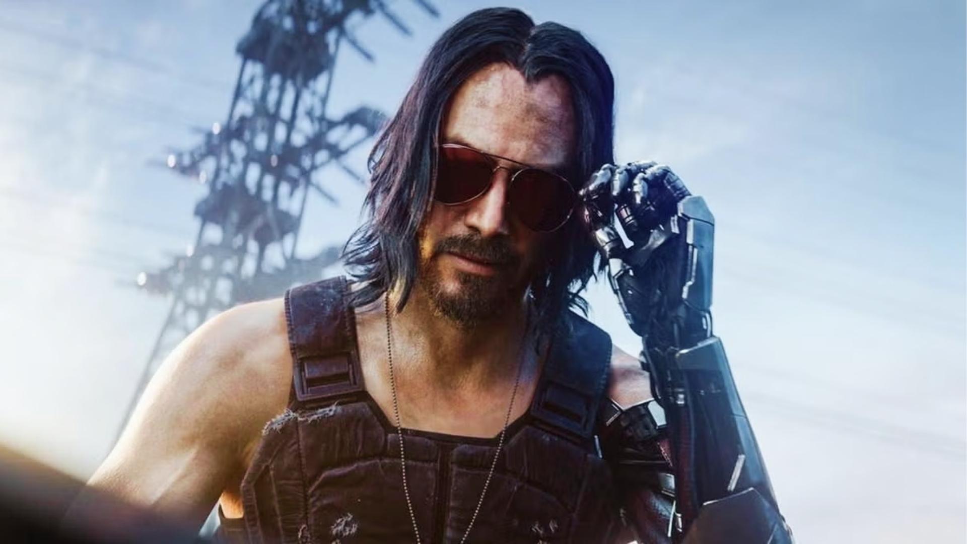 Johnny Silverhand with long black hair, red aviator sunglasses, and cybernetic silver arm adjusts glasses beside an industrial tower in sunlight.
