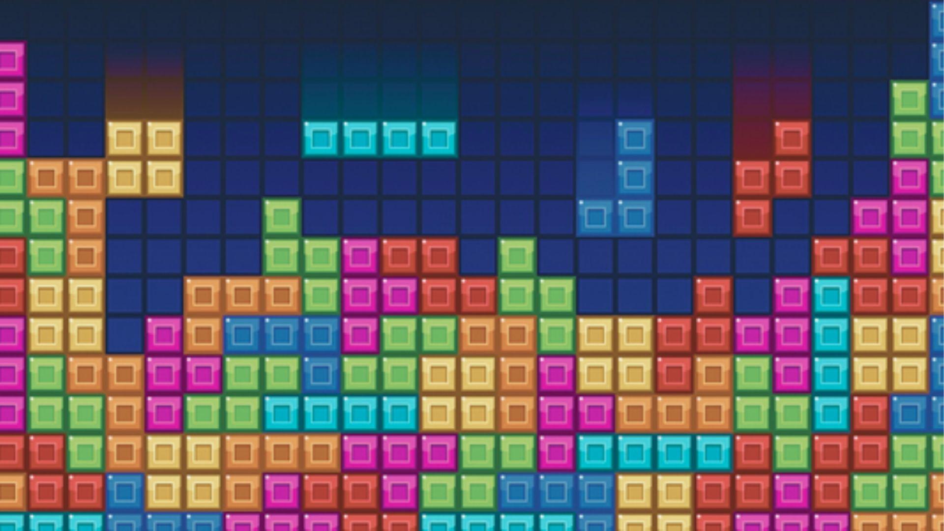 Gameplay screen from the puzzle video game Tetris showing colorful falling blocks on a dark grid.