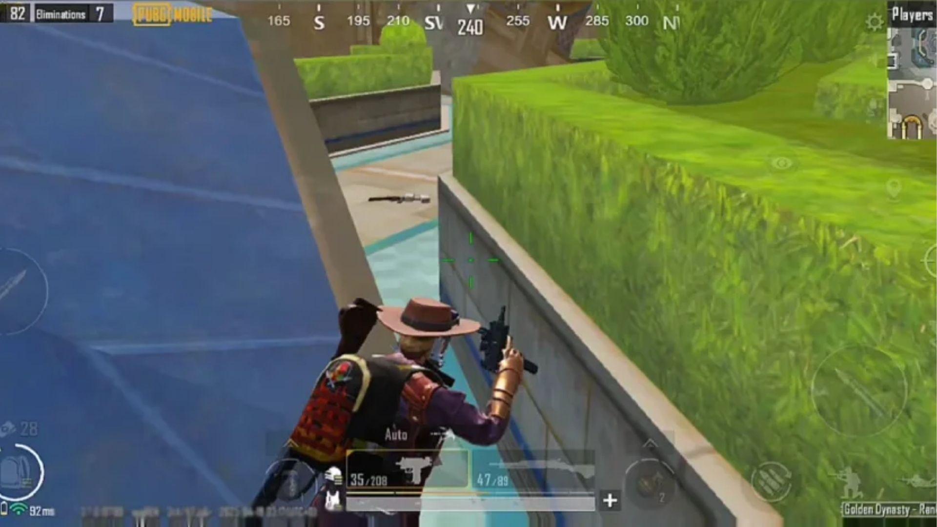 PUBG Mobile gameplay screenshot with player wearing hat aiming gun near wall, showing mobile interface for 2026 crossplay guide