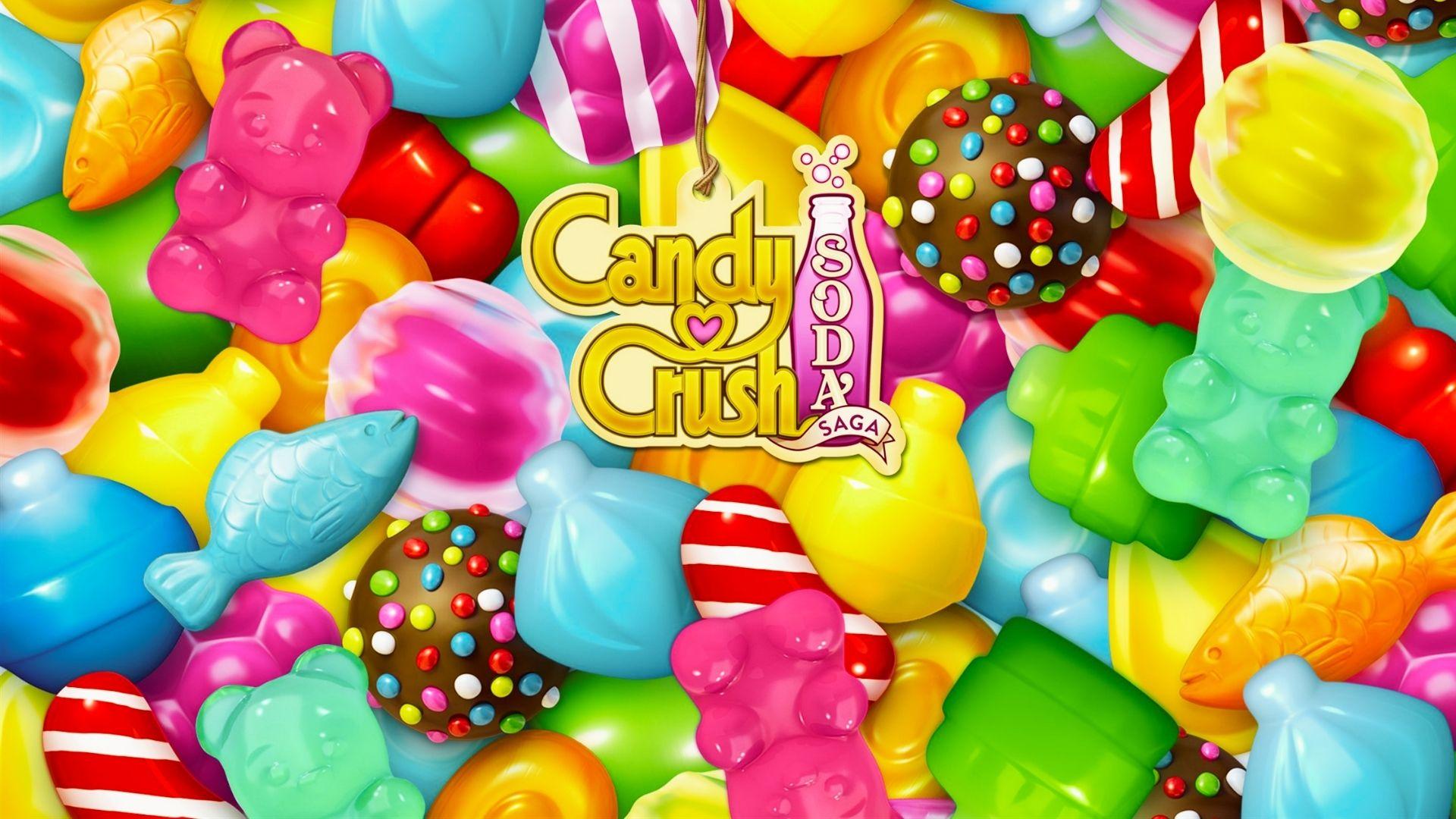 Candy Crush Soda Saga logo surrounded by colorful gummy bears, fish, lollipops, chocolates, candy pieces, bright background