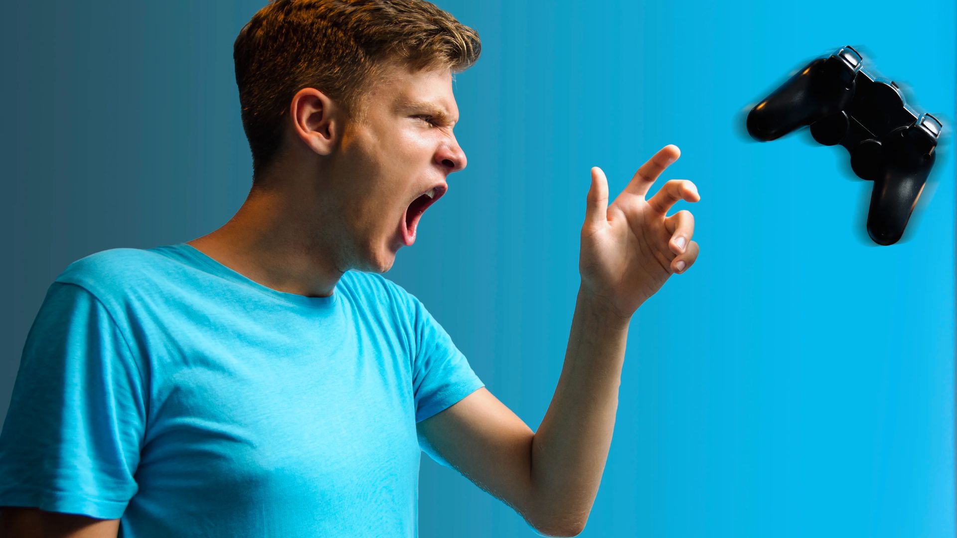 "A young man in a blue shirt angrily throws a gaming controller against a bright blue background, conveying frustration and intensity."
