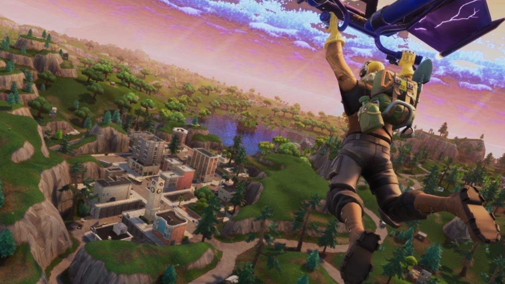 Fortnite character gliding over a green landscape with a city, cliffs, trees, and lake below.